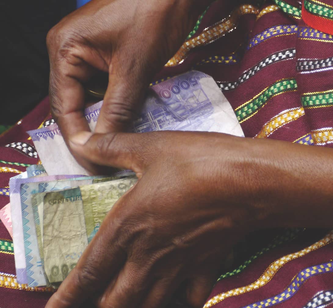 Close Up Of Black Hands On Colourful Fabric Holding Cash Notes