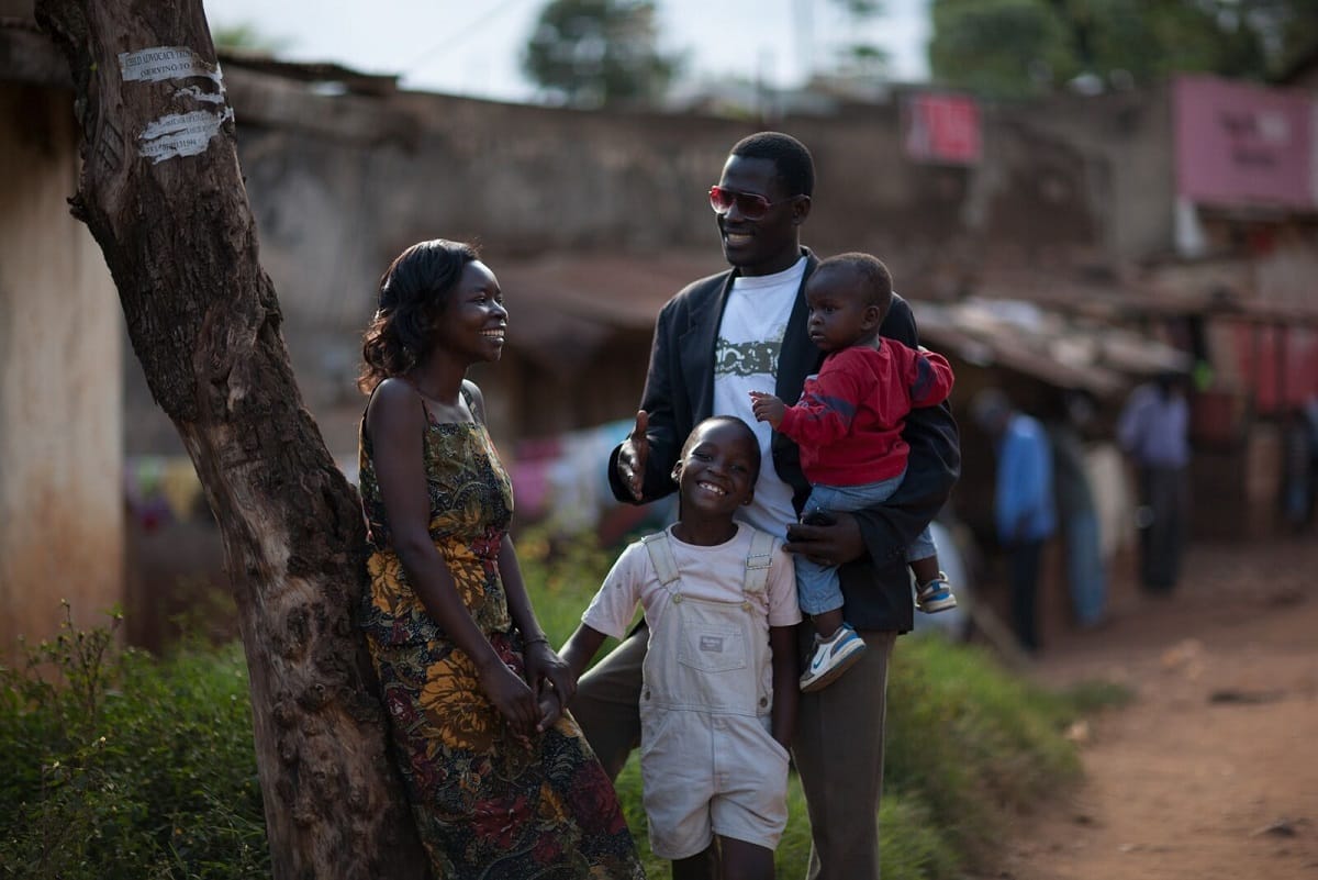 Rwandan Family Of Man, Woman And Two Children Talking And Smiling Outdoors
