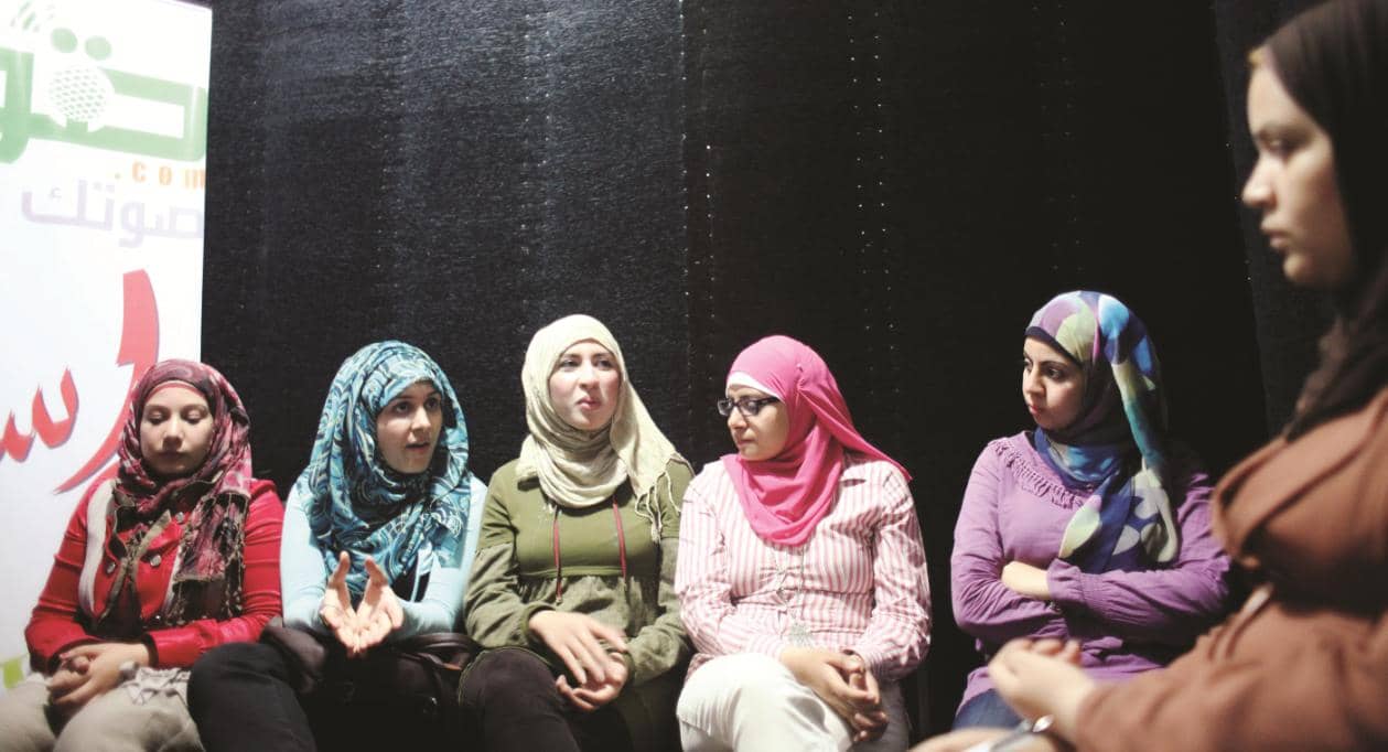 Group Of Young Arabic Women Wearing Headscarves Sitting And Talking To Each Other