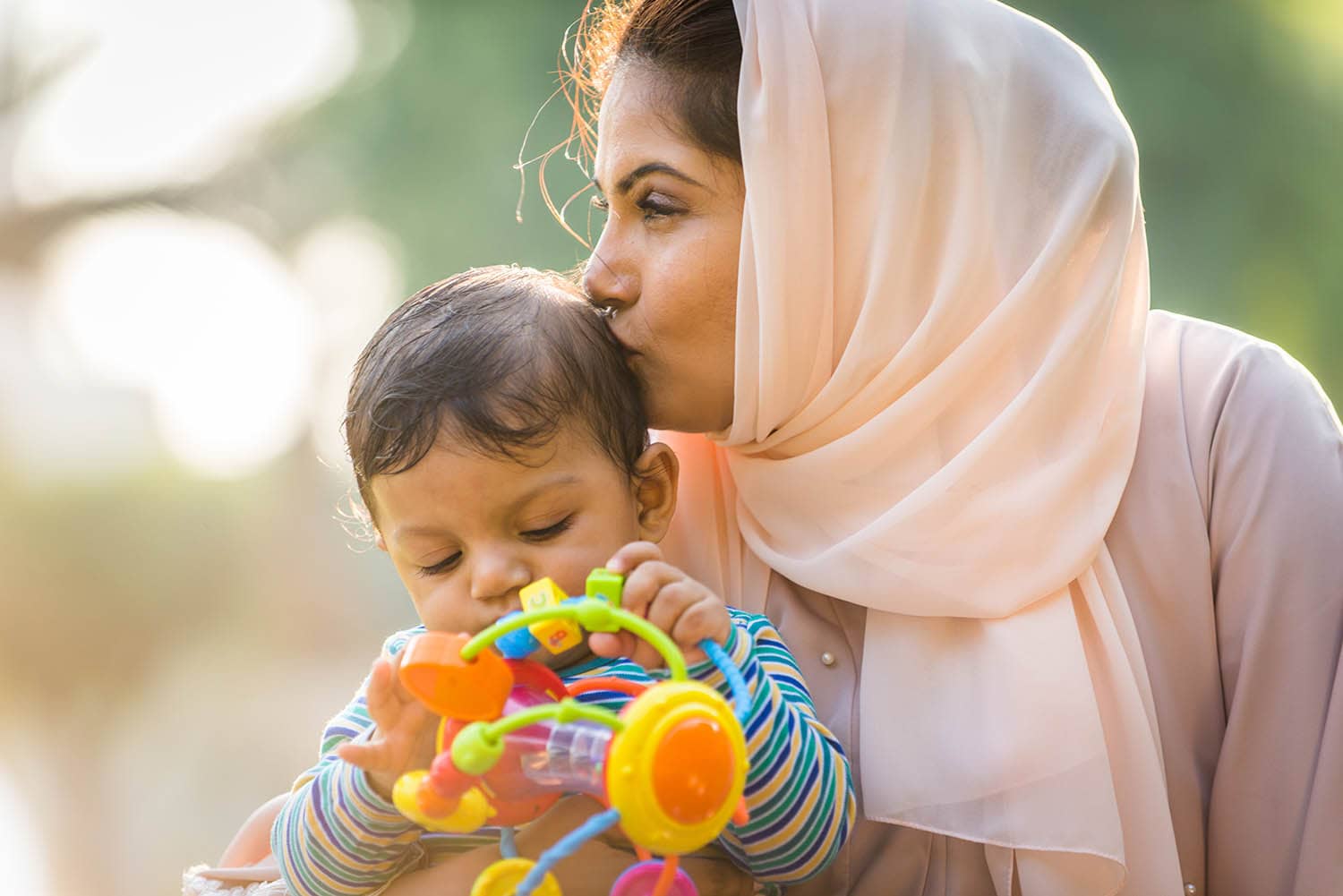 Woman Wearing Headscarf Kissing Her Baby On The Head