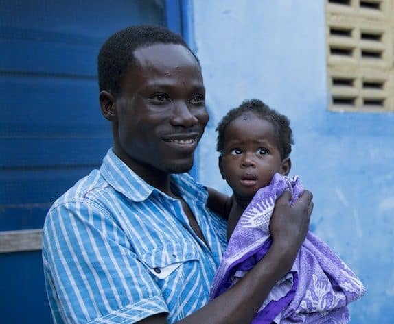 Photo of smiling African man holding a young child
