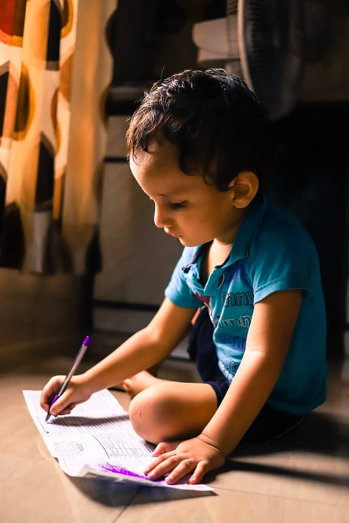 Young child sitting and colouring in paper