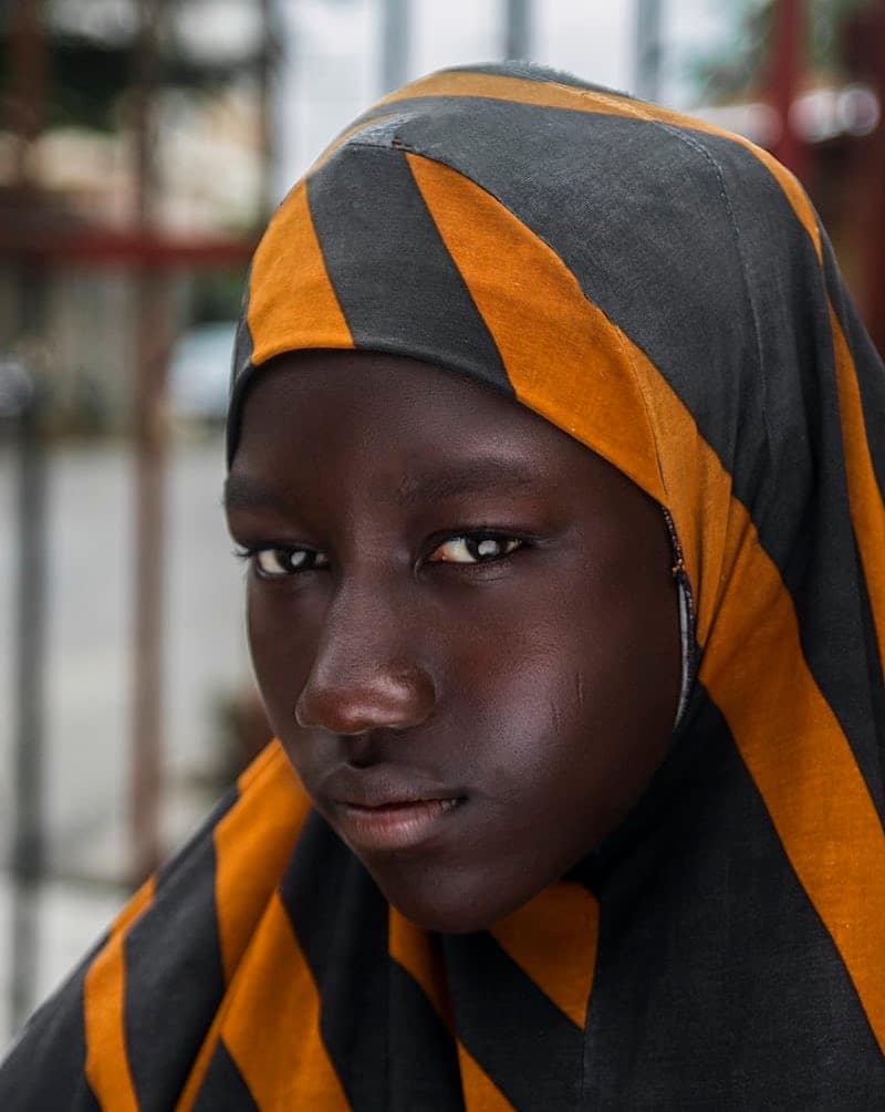 Close up of young black girl in headscarf looking at camera