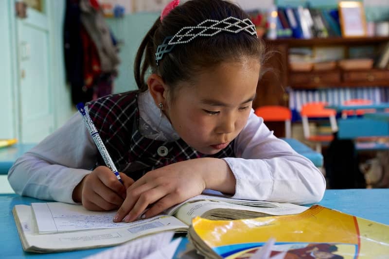 Photo of female southeast Asian schoolchild writing in exercise book