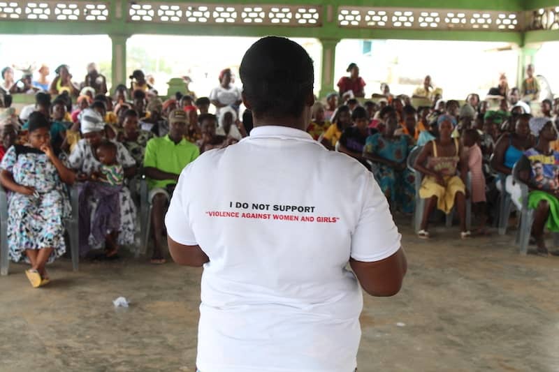 Photo Of African Facilitator And Large Group Of Participants, The Facilitator's Shirt Says I Do Not Support Violence Against Women And Girls
