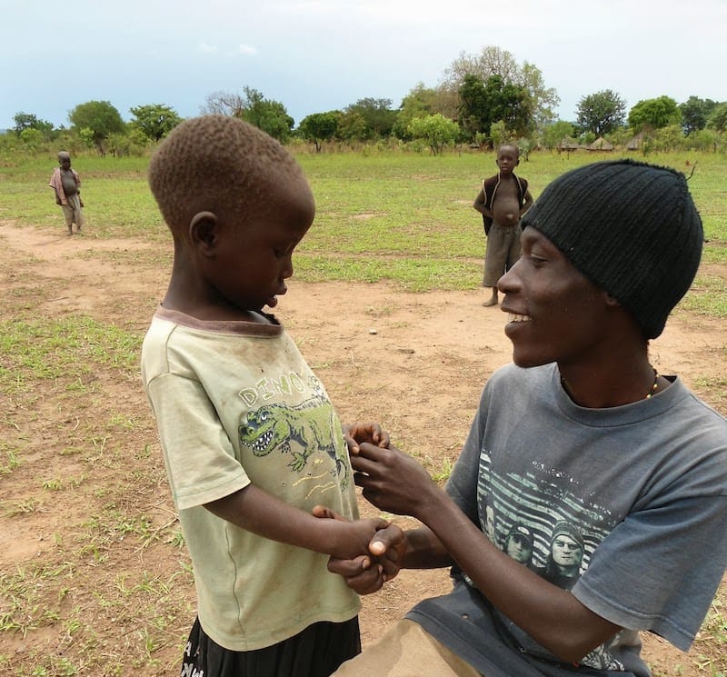 Photo of African man holding hands with young child