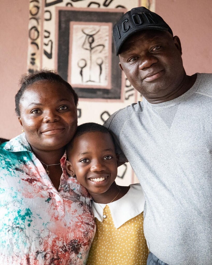 A Black Couple With Their Daughter, Smiling At The Camera