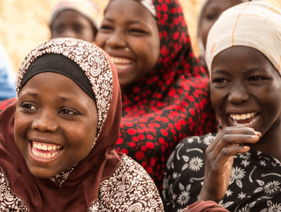 A group of three black Muslim girls are laughing at something.