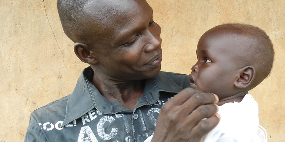 Photo of African man holding and smiling at young child