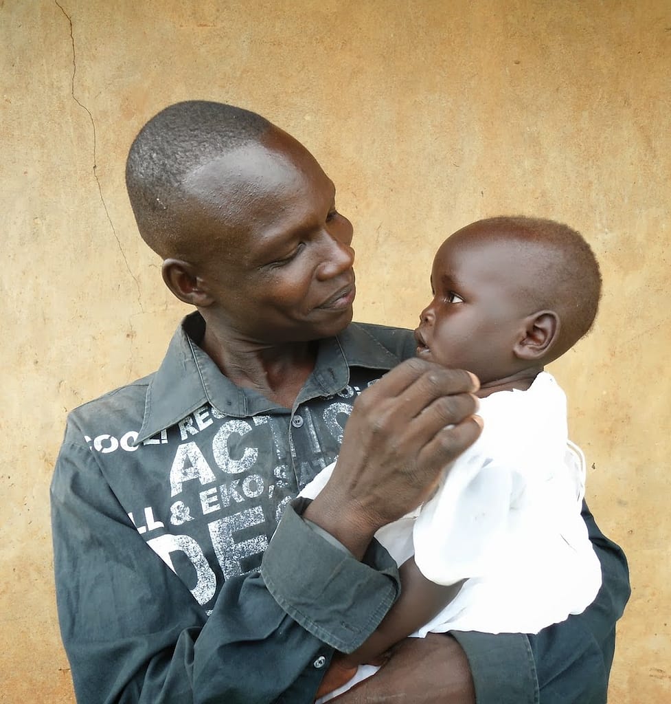Photo of African man holding and smiling at a baby