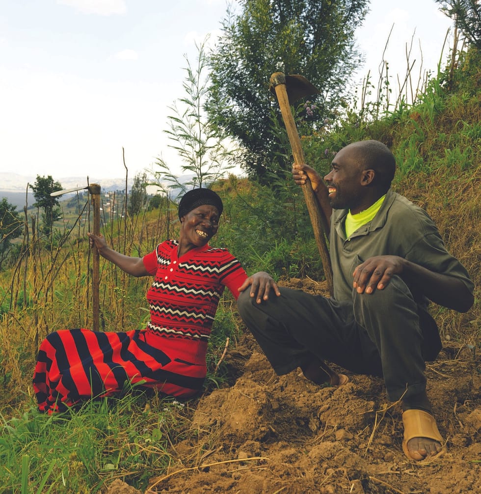 Black couple sitting in a field, smiling at each other, the woman has her hand on the man's knee