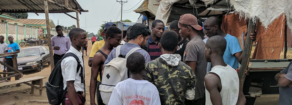 Group of young black men gather at an outdoor market