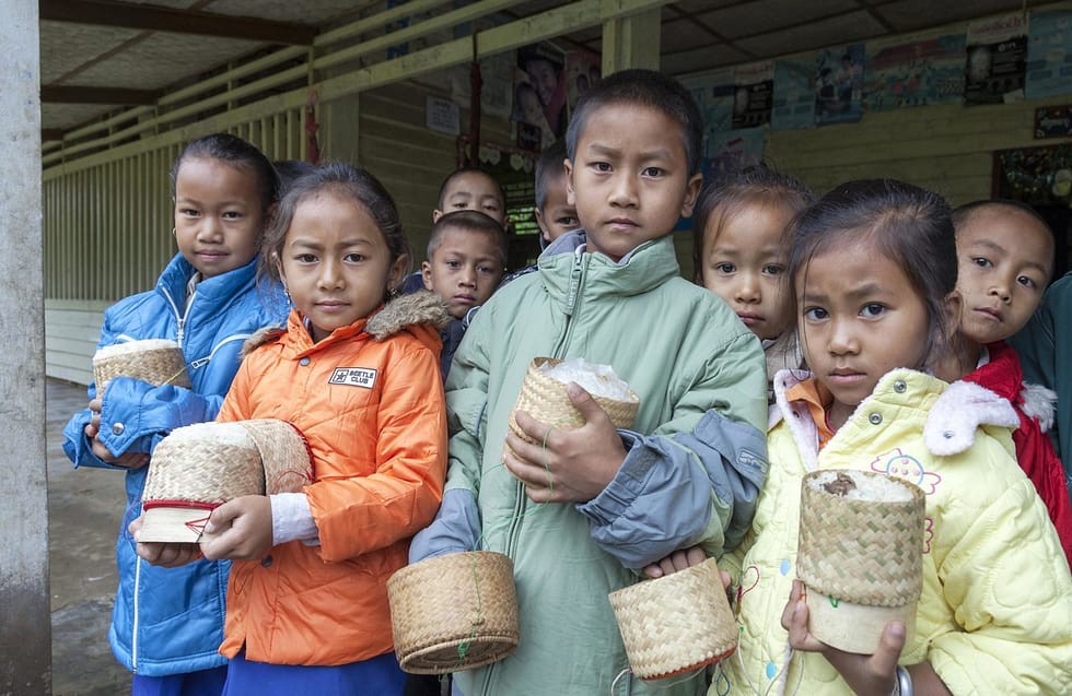 Group of southeast Asian children holding baskets of steamed rice