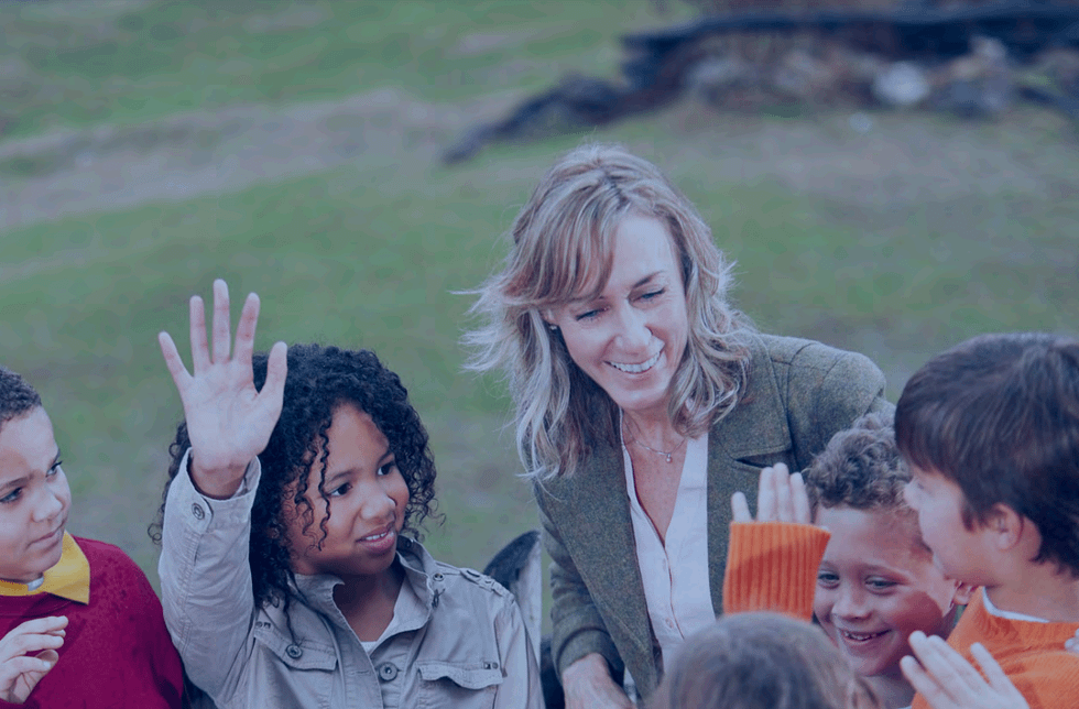 A white woman with children and engaging and laughing with them.