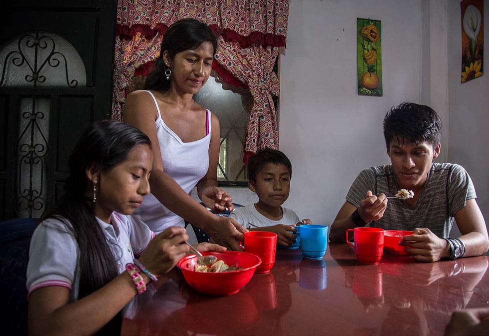 Ecuadorian woman and three children at the dinner table, the children are eating and drinking